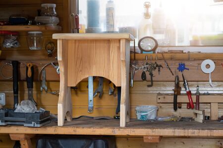Oak wooden stool chair after resoring and repair at carpentry woodwork workshop with tools and...