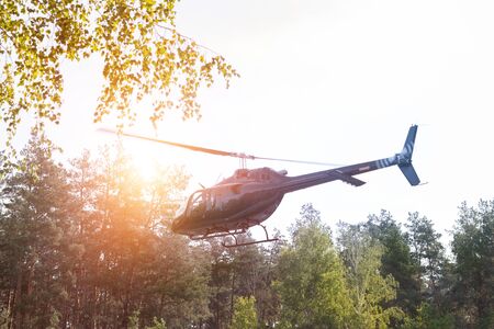 Black private modern luxury helicopter taking off or landing at suburban helport near forest at...