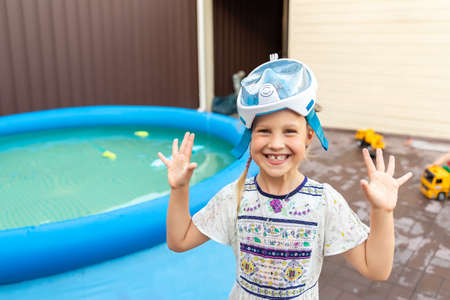 Cute adorable caucasian blond little girl making experiment try diving in pool with full face snorkel mask in inflatable pool at house yard. Stay home lockdown quarantine new normal. Travel conceptの写真素材