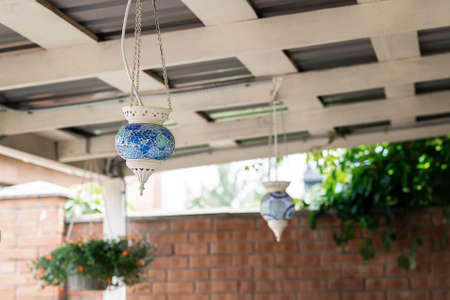Turkish traditional oriental blue mosaic galss lantern lamp hanged on wooden roof of pergola patio canopy at backyard outdoor. Home decoration design.の写真素材