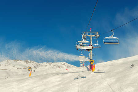 Scenic panoramic view of alpine peaks with ski lift ropeway on hilghland mountain winter resort and...