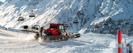 Red modern snowcat ratrack with snowplow snow grooming machine preparing ski slope piste hillalpine skiing winter resort Ischgl in Austria. Heavy machinery mountain equipment track vehicle. panoramicの写真素材