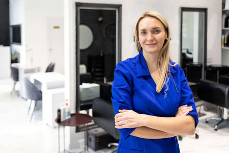 Young attractive confident professional beautician doctor portrait in blue uniform at beauty clinic salon. Cosmetologist specialist doing skincare treatment .Health care therapyの写真素材