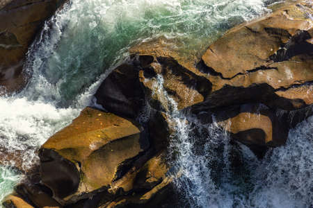 Close-up abstract texture above view of river torrent and clear fresh cold water flowing through...