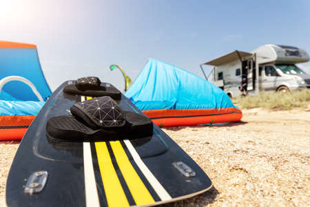 Close-up surf board and kite equipment on sand beach shore watersport spot on bright sunny day...