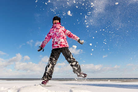 Portrait of cute funny adorable little playful child girl wearing warm snow jacket enjoy having fun playing at park outdoors sunny cold day. Winter christmas holidays leisure time activities outsideの写真素材