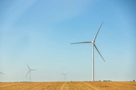 Panoramic landscape view of new white modern wind turbine farm power generation station against...