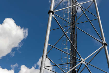Close up perspective pov of modern metal steel mobile 5g network wireless telecom tower against clear blue sky background on bright day. Microwave signal broadband equipment base line station mastの写真素材