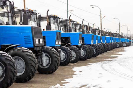 Many different tractors standing in row at agricultural fair for sale outdoors.Equipment for agriculture.Heavy industrial machines presented to agricultural exhibition. Agribusiness leasing conceptの写真素材