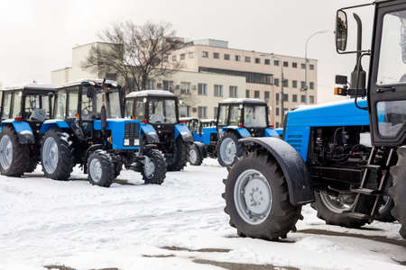 Many different tractors standing in row at agricultural fair for sale outdoors.Equipment for...