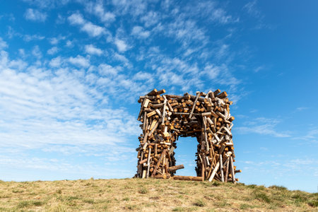 Big square wooden arc of cut round tree logs against vibrant blue sky and bright sun on warm sunny day. Natural material park garden decoration objectの写真素材