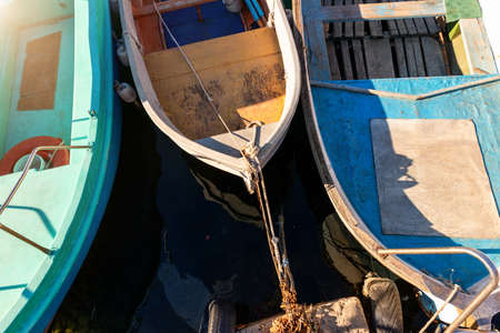 Row of many small old wooden vintage colorful bright fishing ships moored at fisherman village marina clear water bay on bright sunny day. Sea harbor with traditional retro vessels backgroundの写真素材