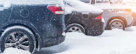 City street driveway parking lot with many cars covered by snow stucked after heavy blizzard snowfall on winter day by dirty snowy pile. Snowdrifts and freezed vehicles. Extreme weather conditionsの写真素材