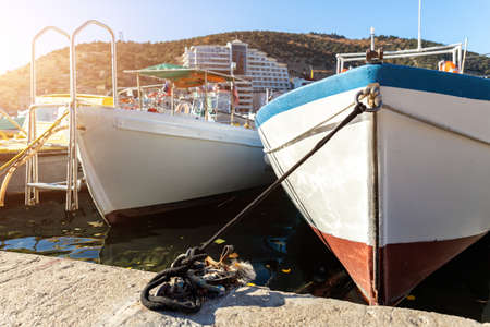 Row of many small old wooden vintage colorful bright fishing ships moored at fisherman village marina clear water bay on bright sunny day. Sea harbor with traditional retro vessels backgroundの写真素材