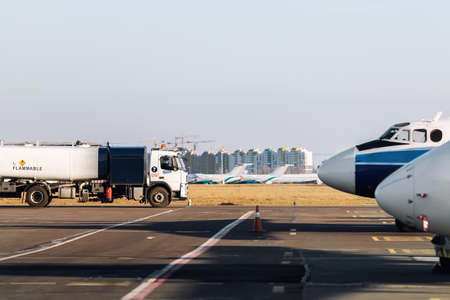 Side view small modern fuel tanker truck driving on airfield taxiway for aircraft refueling. Cistern lorry aviation gasoline. Plane gas supply. Airport maintenance handling service vehicle equipmentの写真素材