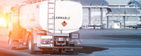 Back view small modern fuel tanker truck driving on airfield taxiway for aircraft refueling. Cistern...