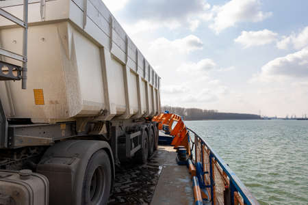 Close-up detail view of big industrial hopper truck body loaded on cargo ferry boat sailing on river...