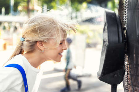 Profile side close-up view cute little blond kid girl enjoy fresh moisturized air blowing from big...