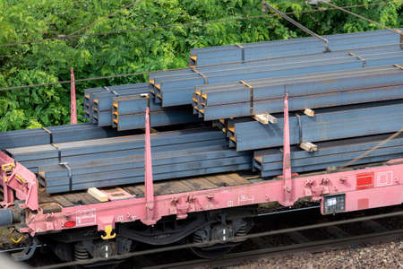 Heap pile heavy raw rusted steel iron beam girders loaded on railroad cargo freight carriage. Metal goods factory plant products shipping and logistics. Metallurgy industrial transportation serviceの写真素材