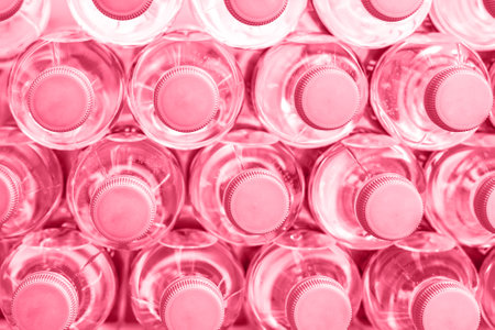 Rows of many transparent plastic bottles with drinking water supply in white refrigerator toned Color of the year 2023 Viva Magenta. Healthcare and dehydration prevention. Mineral water stack storageの写真素材