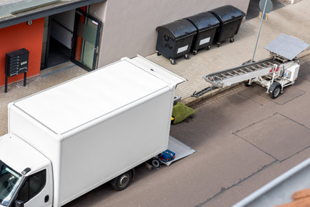 Mover service lifting ladder cargo crane platform vehicle van parked at city street. Retractable furniture elevator machine car pickup truck rental company for relocation and house moving deliveryの写真素材