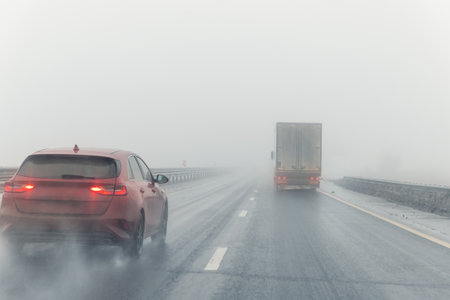 Driver POV on traffic on blue foggy misty rainy slush highway intercity road with low poor visibility on cold winter autumn morning. Seasonal bad rainy weather accident danger warning. car fog lightの写真素材