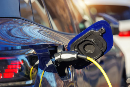 Close-up modern electric plug-in hybrid car parked near fast charger charging station point in...