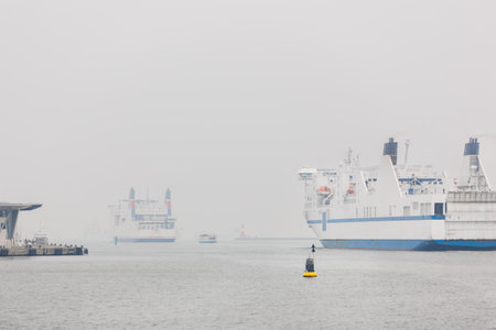 Big modern ferry ship navigate from Rostock harbor Warnemunde bay foggy spring autumn morning misty...