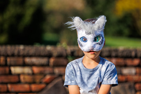 Cute young little kid girl wear cat furry mask enjoy have fun playing outdoors in forest street park. Children therian wild animal character trendy fan culture. Teenager social expression hobbyの写真素材