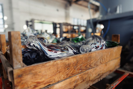 Many colorful glass vases in wooden box at glass blowing manufacture factory  with furnace equipment...