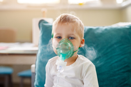 Cute little kid boy wear use medical nebulizer mask inhaling steam respiratory therapy lungs rsv allergic disease cure. Portrait child treating seasonal respiratory bronchitis cough medical inhalerの写真素材