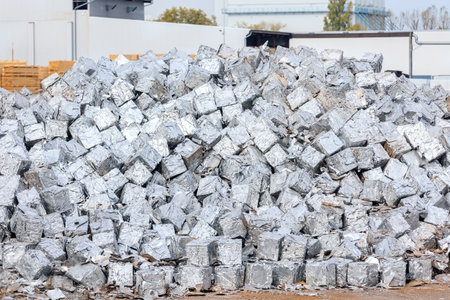 tacks of pressed aluminum cubes glisten in bright light, hinting at large-scale recycling operations. Reflective surfaces highlight an industrial push toward sustainability and efficient resource useの写真素材
