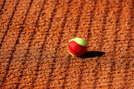 clay tennis court with scattered two-tone balls under bright sunlight. The net and long shadows create a dynamic atmosphere, emphasizing movement and competitionの写真素材