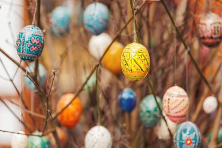 Colorful Easter eggs hanging on delicate branches bring joyful spring mood with intricate patterns...