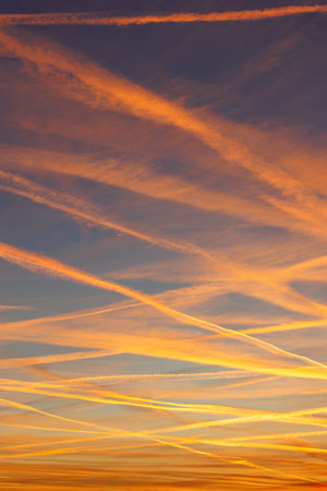 Scenic dramatic colorful sunset or sunrise sky landscape many aircraft jet contrail crossing. Natural beautiful dawn background wallpaper. Twilight time cloudscape. Europe aircraft trafficの写真素材