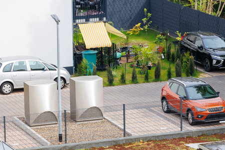 Modern residential apartment building home yard with modern heat pumps, parked cars and a small...