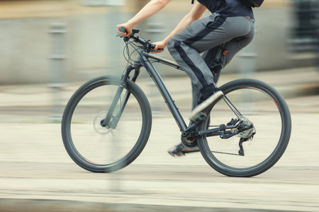 Man in sport suit riding fast black bicycle on European city street dynamic motion blurred background on sunny day. Urban bike commute work ride employee healthy lifestyle eco-friendly transportの写真素材