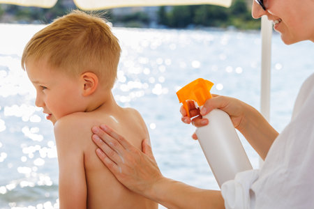 Mother applying sunscreen protection creme on cute little baby boy kid hand. Mum using sunblocking lotion to protect baby from sun during summer sea vacation. Child healthcare travel vacation timeの写真素材