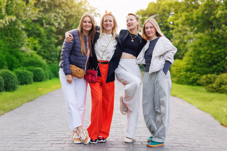 Portrait four cheerful young adult women friend walk street park  european german town city enjoy have fun laughing sunny day together. Female persons friendship celebration party event weekendの写真素材
