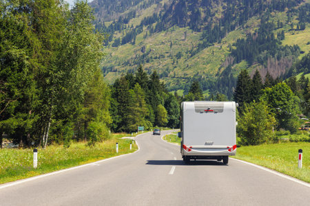 Scenic back view modern white family rv camper van vehicle drive Europe curvy road alpine pass...