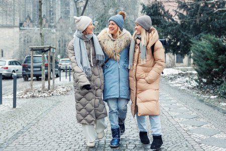 Three cheerful young adult women friend walk Magdeburg street old european uk german town city street enjoy having fun laughing cold winter day together. Female persons friendship celebration weekendの写真素材