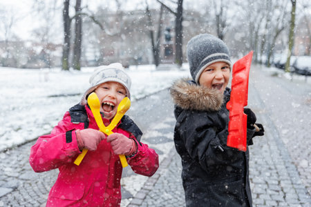 Portrait two cute little kids boy girl enjoy having fun playing with snow toys city street park  family on snowy cold winter day. Children carefree joy walk outdoors. Happy childhood healthcareの写真素材