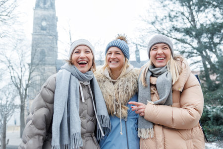 Three cheerful young adult women friend walk Magdeburg street old european uk german town city street enjoy having fun laughing cold winter day together. Female persons friendship celebration weekendの写真素材