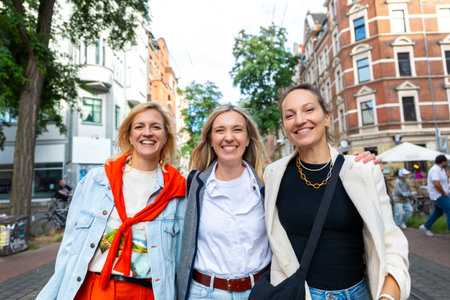 Three cheerful young adult women friend walk street old european german Hannover city street enjoy having fun laughing sunny day together. Female persons friendship celebration party weekendの写真素材