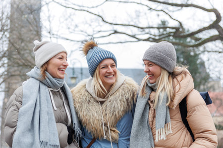 Three cheerful young adult women friends walk Magdeburg street old european town city street enjoy...