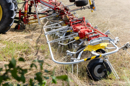 Agricultural machinery work field spread dry hay summer harvest season. Tractor powered tedder...