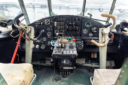Vintage aircraft cockpit interior analog instruments, control levers worn pilot steering handles. Retro aviation technology and mechanical flight dashboard show historic aerospace engineering details
