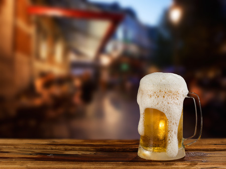 cold mug of beer with foam on the background of the streetの写真素材