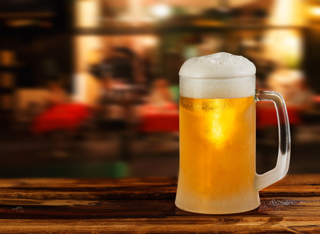 cold glass mug of beer with foam on the background of the streetの写真素材