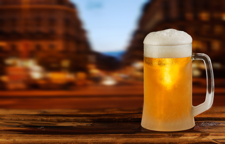 cold glass mug of beer with foam on the background of the streetの写真素材